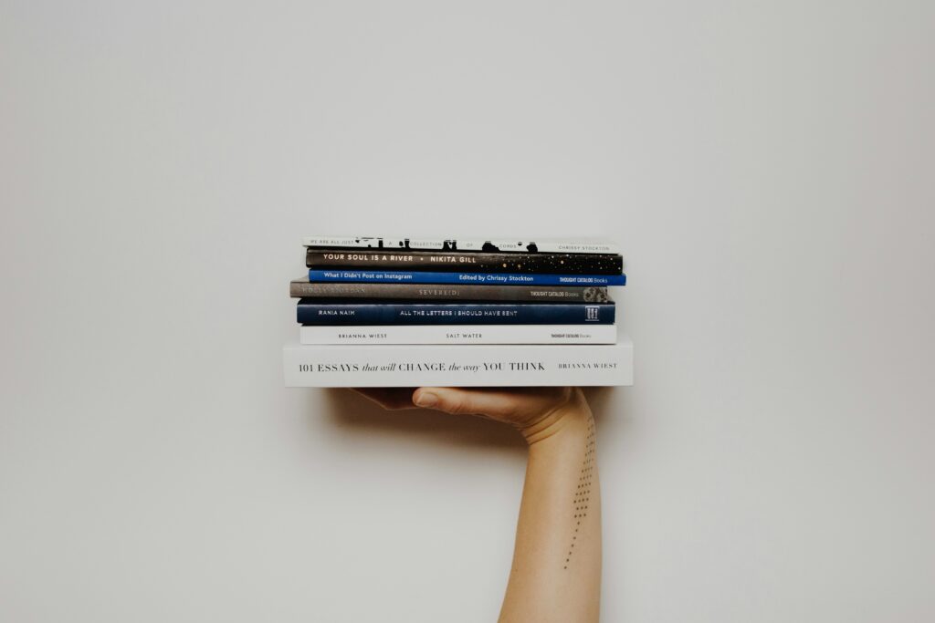 Une main tendue vers le haut soutien des livres de poche empilés les uns sur les autres.