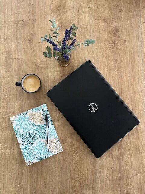 Illustration de l'activité de rédactrice web : un ordinateur et un calepin sont posés sur une table.